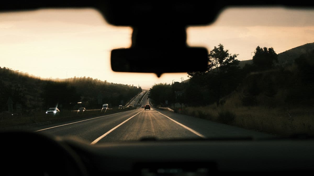 The view through a car windshield toward a low sun on a highway