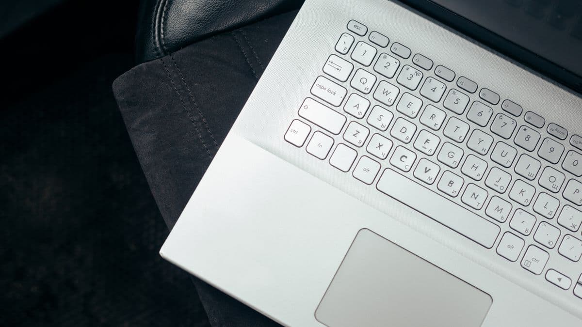A silver laptop open on a dark car seat