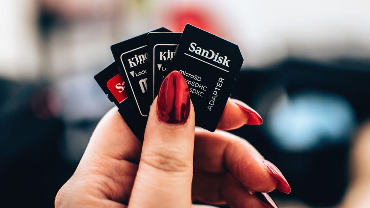 A hand holding several microSD cards and adapters