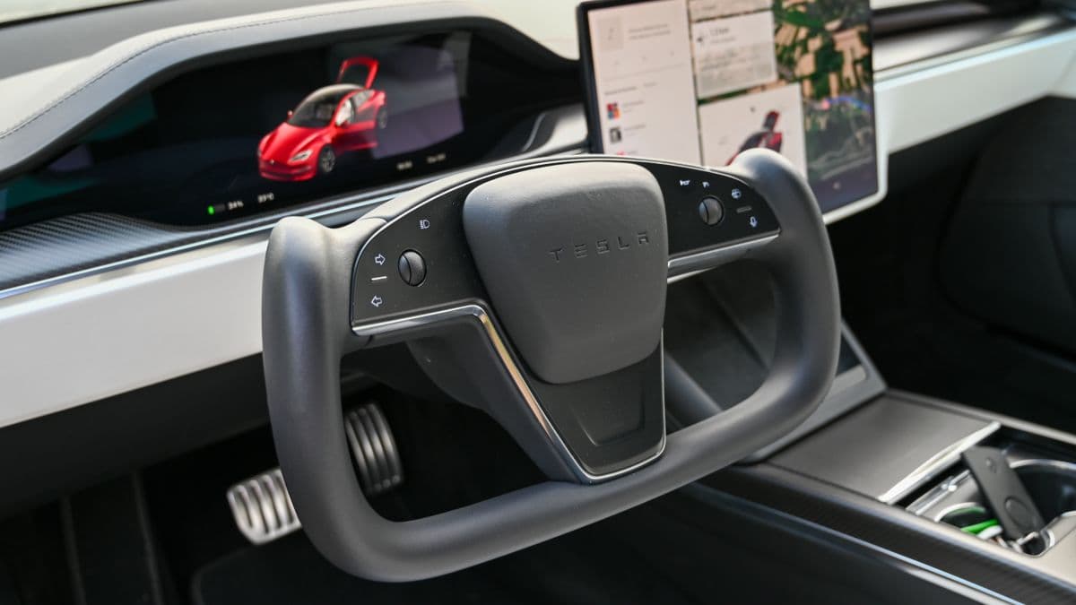 A Tesla interior showing the steering wheel, screens and center console