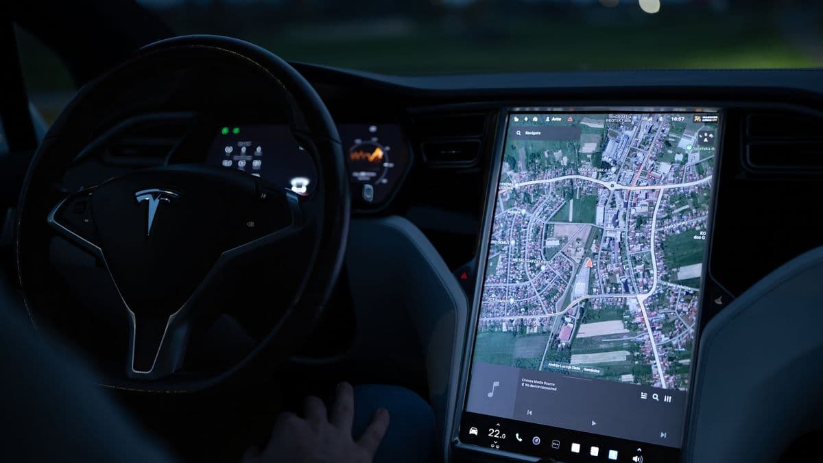 The illuminated touchscreen and steering wheel of a Tesla at night