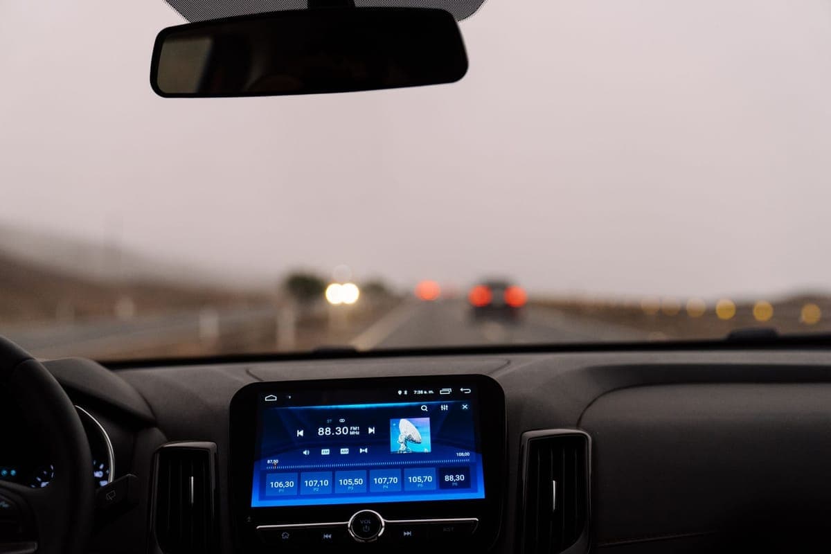 The view forward past a car's rear-view mirror and across a bare dashboard on an open road